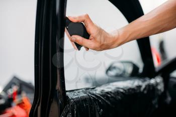 Male specialist work with car, tinting film installation process, tinted auto glass installing procedure