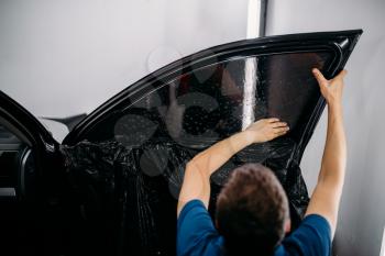 Male specialist with drier, car tinting film installation process, tinted auto glass installing procedure