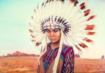 American Indian woman against mountain valley, Cherokee, Navajo. Headdress made of feathers of wild birds
