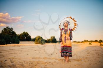 Portrait of American Indian girl in traditional costume and headdress made of feathers of wild birds