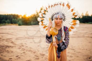 Young American Indian woman in traditional costume and headdress made of feathers of wild birds