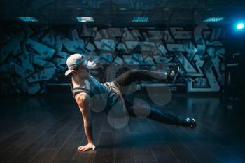 Young breakdance performer dancing in studio. Modern urban dance style. Male dancer