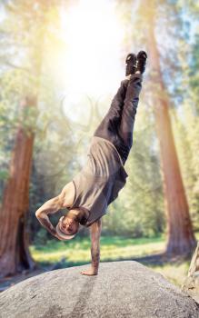 Breakdance performer, upside down motion in the forest. Modern dance style. Male dancer