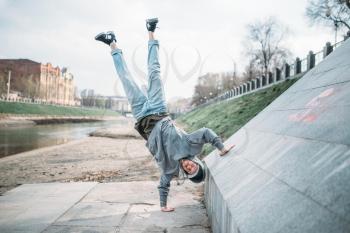 Hip hop performer, upside down motion on the street. Modern dance style. Male dancer