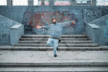 Rap performer posing on the steps, street dancing. Modern urban dance style. Male dancer