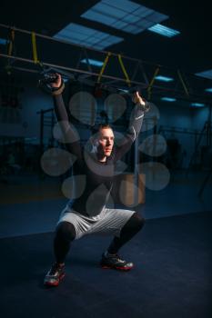 Strong sportsman on training, stretch endurance workout with ropes in gym. Energy exercises in sport club