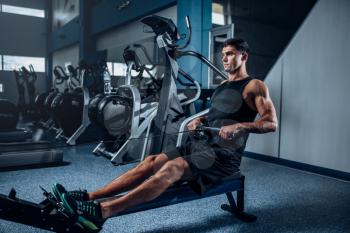 Muscular man workout on exercise machine. Active sport training in gym