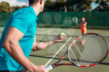 Male and female players with rackets on outdoor tennis court. Summer season active sport game