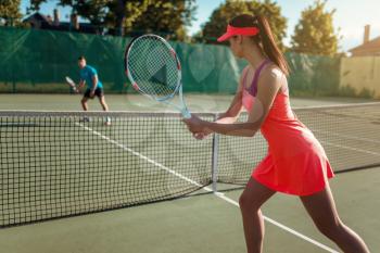 Couple playing tennis on outdoor court. Summer season active sport game