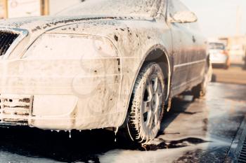 Wet vehicle in foam, automobile in suds, car wash. Carwash station