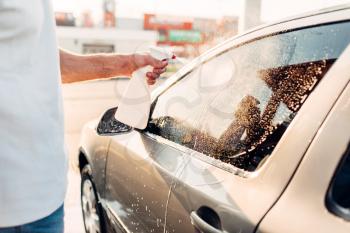 Man rubbing vehicle with car polish after washing. Automobile polishing on carwash station