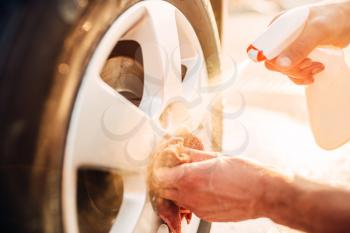 Male hands cleans disk with car rim cleaner, carwash. Carwashing station