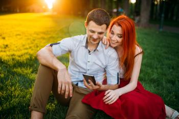 Love couple happy together, romantic date in summer park on sunset. Attractive woman and young man leisure on a grass