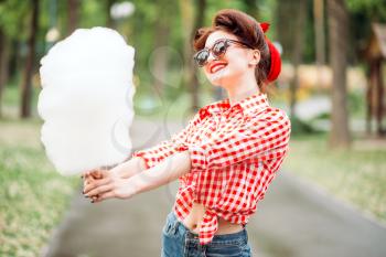 Sexy pin up girl in sunglasses with cotton candy on stick, retro american fashion. Attractive woman in pinup style