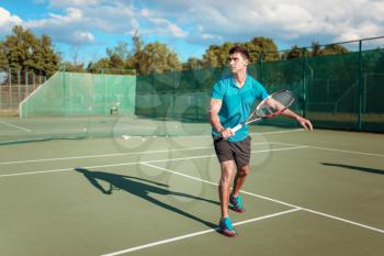 Athletic male tennis player plays on outdoor court. Summer season active sport game. Happy leisure