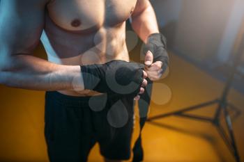 Muscular male person hands in black bandages. Boxing workout, mens sport. Boxer in handwraps