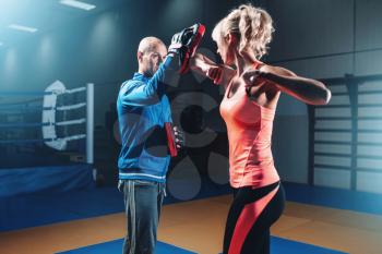 Woman on self defense training with male trainer, fighting workout in gym, martial art