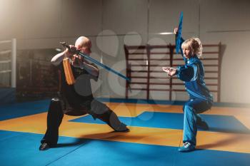 Wushu fighters, man and woman with swords, martial arts culture