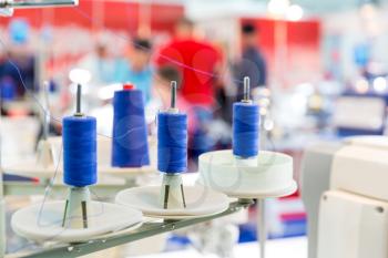Spools of blue threads on sewing machine, closeup. Cloth factory, weaving, textile production, clothing industry
