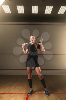 Attractive young woman with squash racket, indoor training club on background