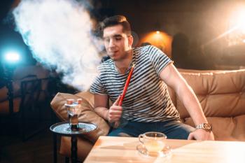 Young man smoking and relaxation at hookah bar. Tobacco smoke, night lifestyle
