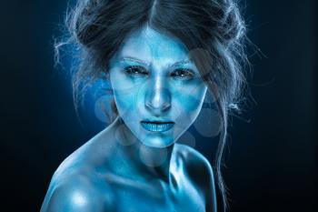 Fantasy woman with blue frost makeup and skin. Ice queen, body art, fluorescent cosmetics