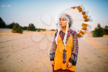 Portrait of American Indian girl in traditional costume and headdress made of feathers of wild birds