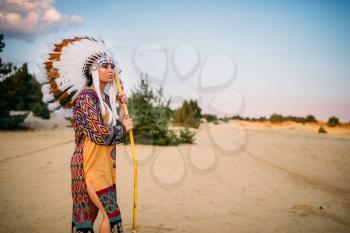 American Indian woman against mountain valley, Cherokee, Navajo. Headdress made of feathers of wild birds