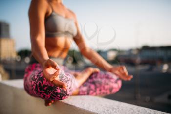 Female person, relaxation in yoga pose, city on background. Yogi meditation exercise outdoors