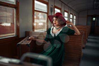 Beautiful woman in retro train, old wagon interior. Railroad voyage. Vintage journey