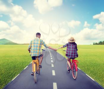 Love couple riding on vintage bikes. Romantic journey of young man and woman. Boyfriend and girlfriend together outdoor, retro bicycle