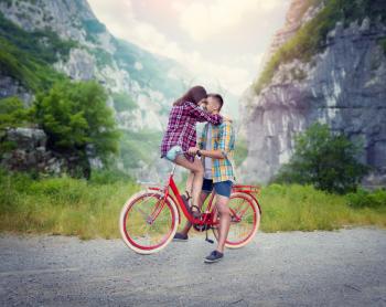 Boyfriend and girlfriend kissing on retro bike. Love couple with vintage bicycle. Young man and woman happy together outdoor, nature on background