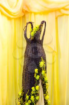 Beautiful rattan dress decorated with flowers, nobody, yellow curtains on background. Wooden cloth