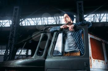 Stalker, alone traveler pose on abandoned military vehicle. Danger zone, mysterious adventure in deserted place