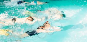 Children swimming underwater in pool. Kids diving with colorful flippers and goggles in clean blue water. Happy kids in modern sport center. Concept of fun, leisure and recreation.