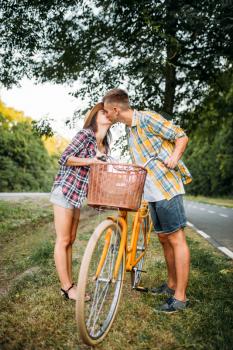 Young man and woman kissing on romantic date. Happy love couple with vintage bike. Boyfriend and girlfriend together outdoor, retro bicycle