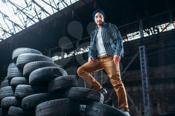 Stalker, traveler climbs a mountain of tires, abandoned factory. Danger zone