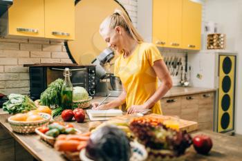 Female person cooking on the kitchen, healthy organic food. Vegetarian diet, fresh vegetables and fruits on wooden table
