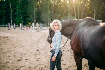Portrait of young woman with brown horse. Equestrian sport, attractive lady and beautiful stallion