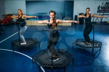 Women group on sport trampoline, fitness training. Female teamwork in gym. Aerobic class