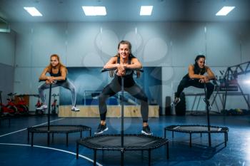 Women on sport trampoline in motion, fitness training. Female teamwork in gym. Aerobic class