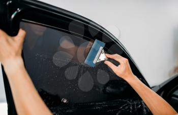 Male specialist with drier, car tinting film installation process, tinted auto glass installing procedure
