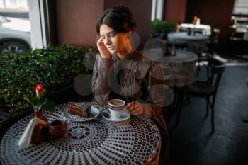 Woman eating delicious chocolate cake in cafe. Delicious dessert and cup of coffee close up shot. Woman sits at table in cafe, selective focus.