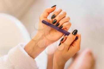 Female person hands with nail file closeup. Manicure procedure, nailcare treatment process