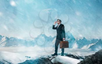Difficult and risky business way concept. Young businessman with leather briefcase in the mountains in bad weather
