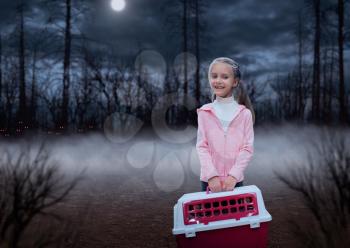 Happy little girl with pink carrier in the forest at night