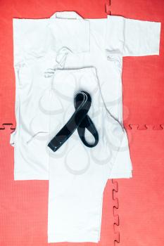 Martial arts, white kimono and black belt closeup, nobody. Fighters insignia