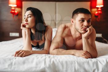 Love couple lies in bed, no sexual desire. Problems in intimate life, impotence, anxiety or depression