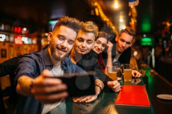 Happy football fans makes selfie on phone camera at the bar counter in a sport pub, victory celebration