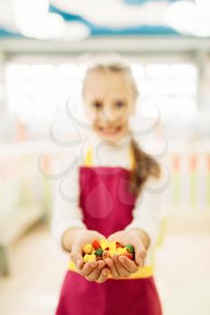 Happy little girl holds in hands handmade caramel sweets. Fresh lollipop in candy store
